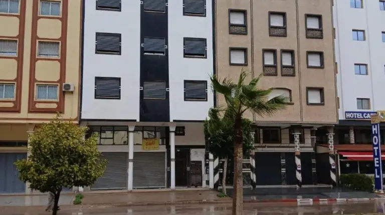 a tall building with a palm tree in front of it at تجزئة الفتح 925 خريبكة 4 in Khouribga