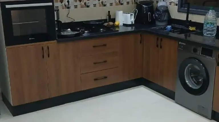 a kitchen with wooden cabinets and a washer and dryer at تجزئة الفتح 925 خريبكة 4 in Khouribga