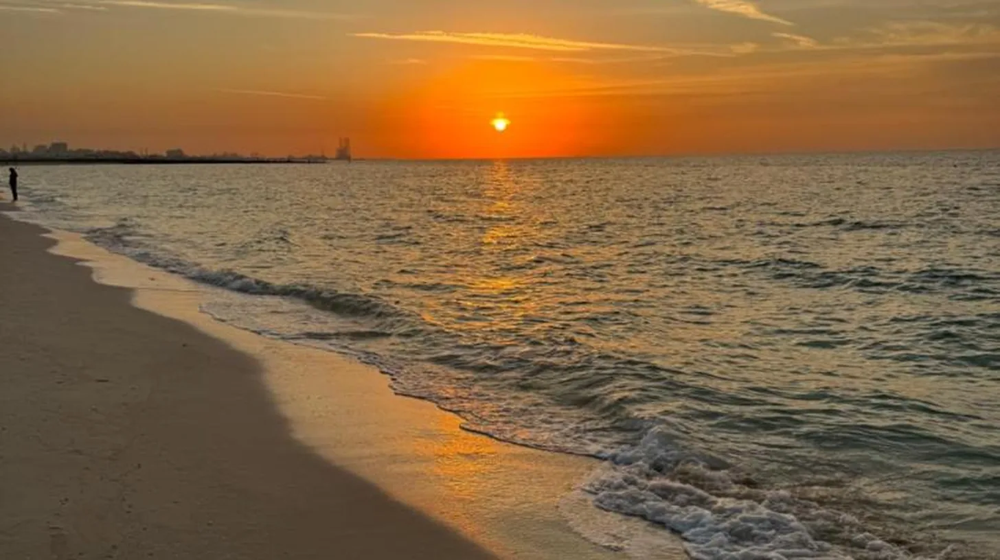 un atardecer en una playa con el océano en Ajman Luxurious Holiday Homes en Ajman