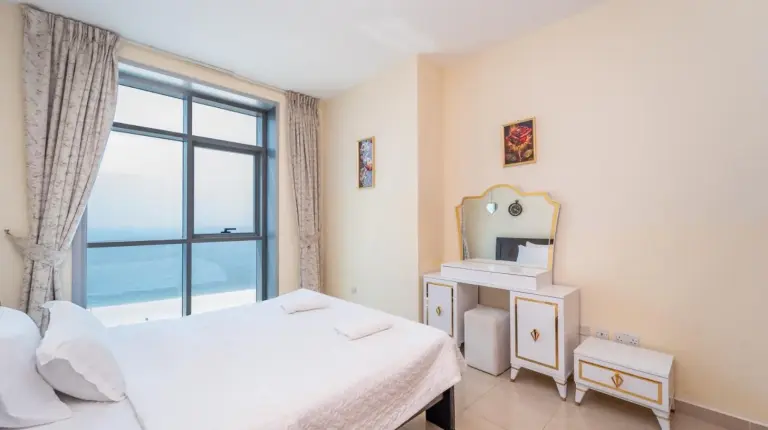 un dormitorio con cama, espejo y ventana en Ajman Luxurious Holiday Homes en Ajman