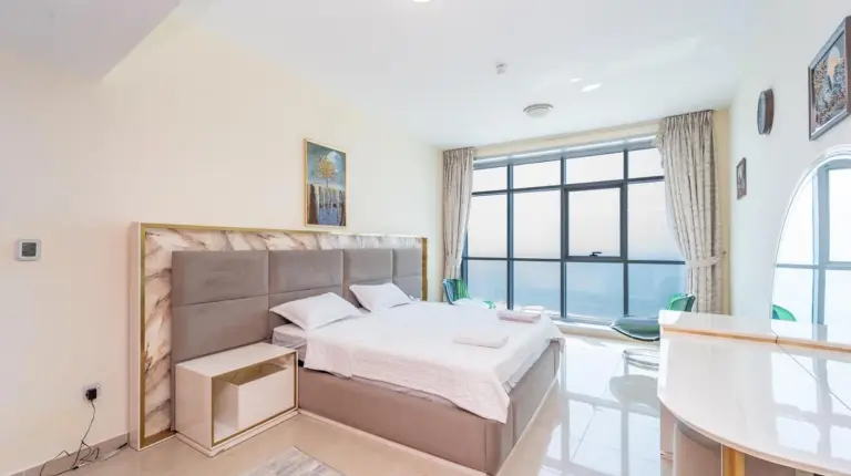 un dormitorio con cama y gran ventana en Ajman Luxurious Holiday Homes en Ajman