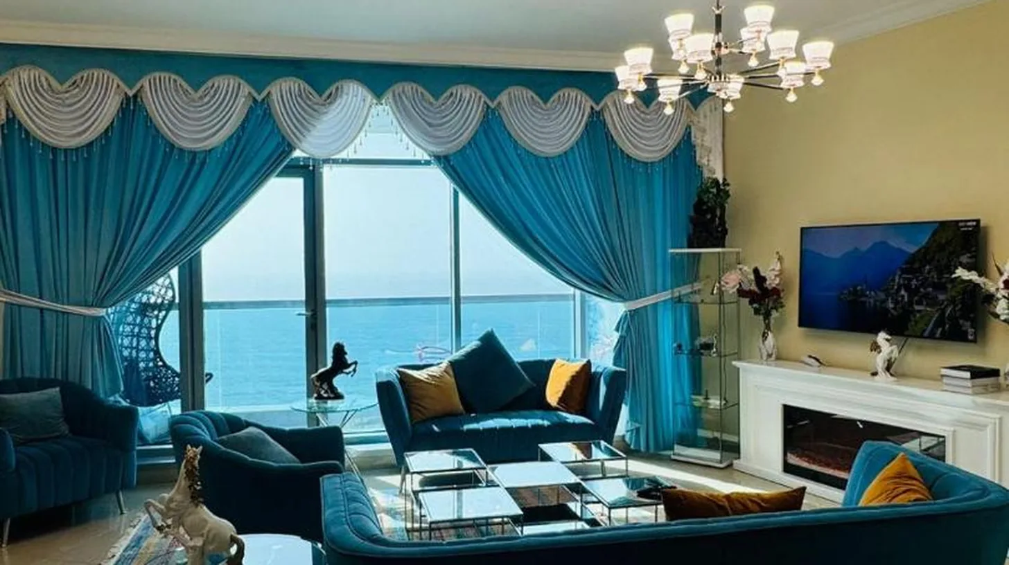 una sala de estar con gran sofá azul y cortinas azules en Ajman Luxurious Holiday Homes en Ajman