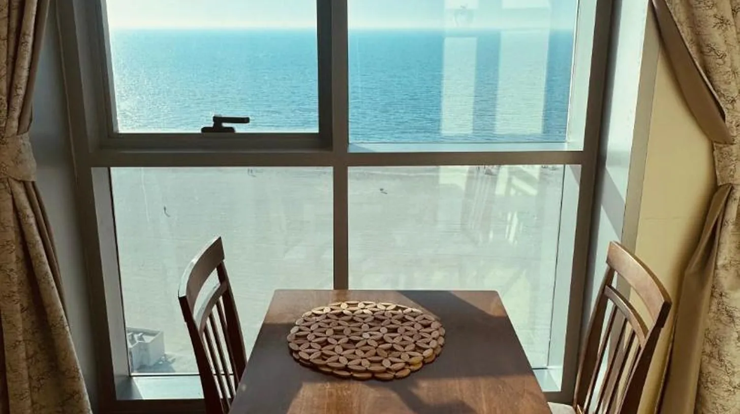 una mesa y sillas en una habitación con gran ventana en Ajman Luxurious Holiday Homes en Ajman