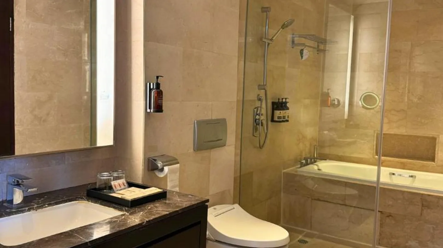 ein Badezimmer mit einer Toilette und einer Glasdusche im Ascott Kuningan Jakarta in Jakarta