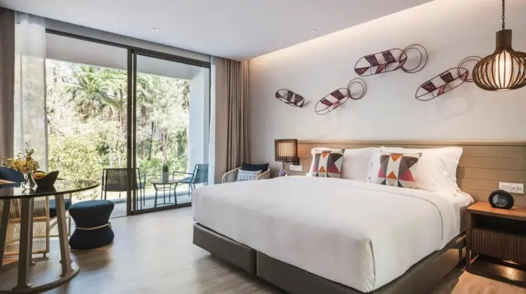 a bedroom with a large white bed and a table at Avani Plus Khao Lak Resort in Khao Lak