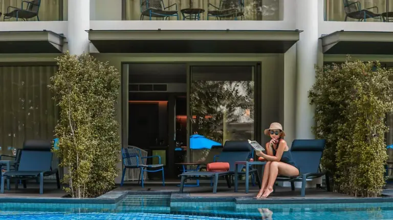 a woman sitting on a chair next to a swimming pool at Avani Plus Khao Lak Resort in Khao Lak