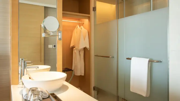 un baÃ±o con un lavabo y una ducha de cristal en Avani Plus Riverside Bangkok Hotel en Bangkok
