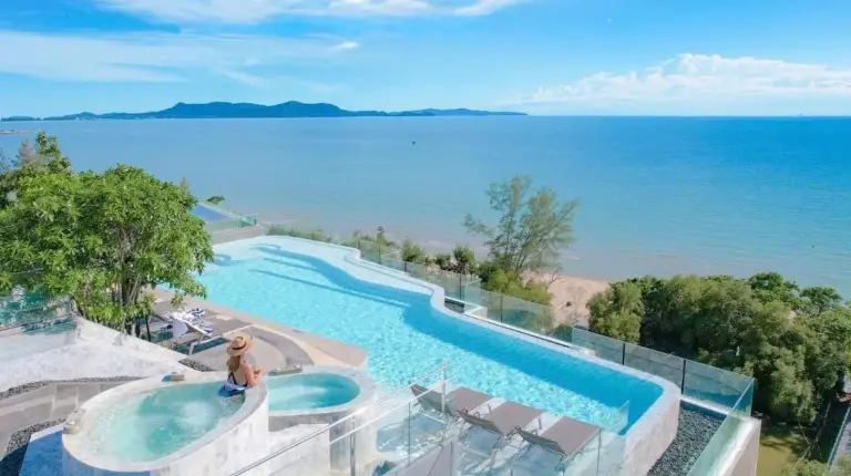 a swimming pool with a view of the ocean at Bayphere Hotel Pattaya JC in Na Jomtien