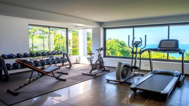 un gimnasio con varias cintas de correr y mÃ¡quinas en una sala con ventanas en BLUE TIGER Luxury Pool Villa Koh Samui en Koh Samui
