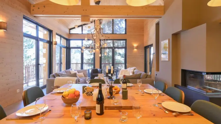 a dining room with a large wooden table with wine glasses at Chalet avec Piscine La Plagne in La Plagne Tarentaise