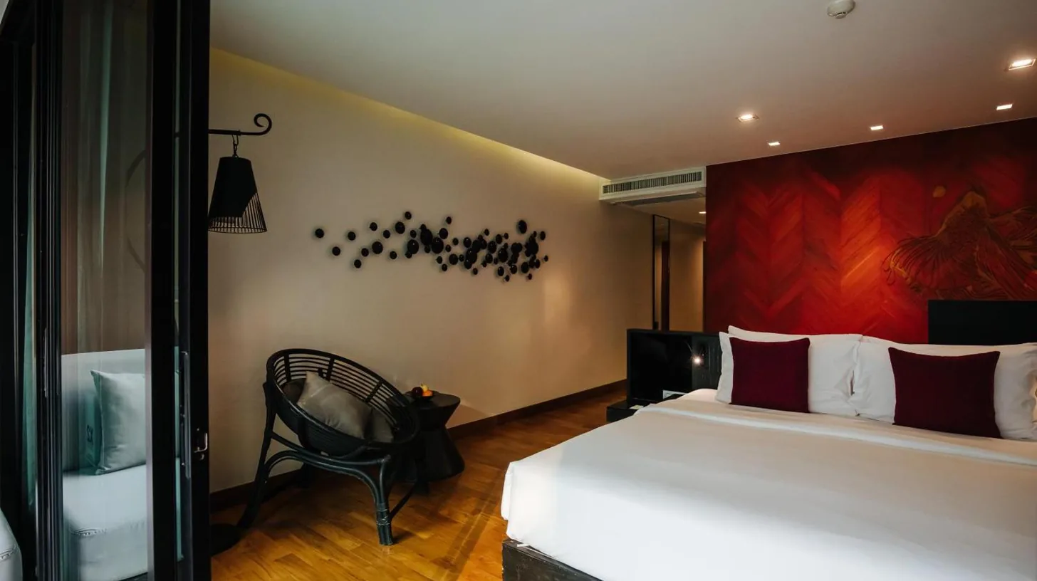 un dormitorio con una cama y una silla en una habitaciÃ³n en Cross Chiang Mai Riverside en Chiang Mai