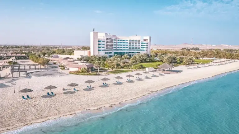 an aerial view of a beach with chairs and umbrellas at Danat Jebel Dhanna Resort in Jebel Dhanna