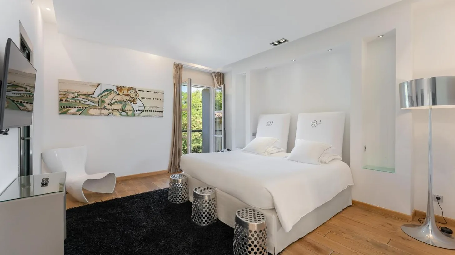 a white bedroom with a white bed and a black rug at Domaine de Verchant & Spa - Relais & Châteaux in Montpellier