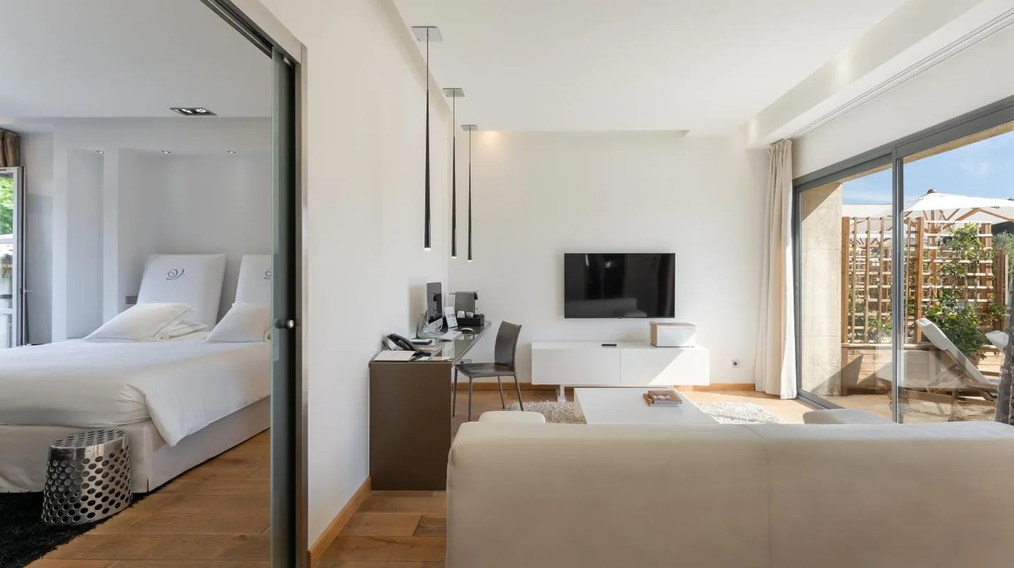 a bedroom with a bed and a couch and a tv at Domaine de Verchant & Spa - Relais & Châteaux in Montpellier