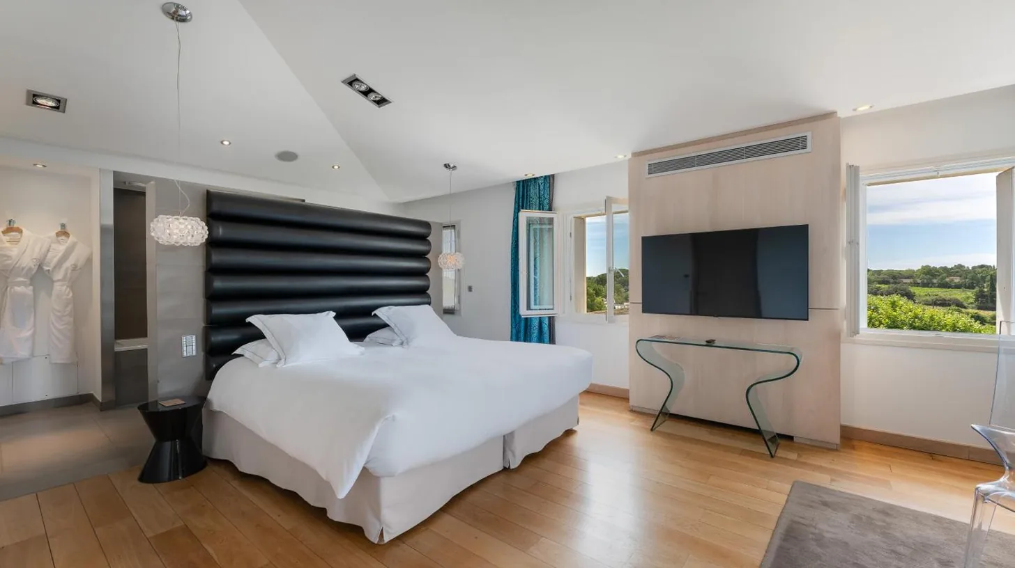 a bedroom with a large white bed and a television at Domaine de Verchant & Spa - Relais & Châteaux in Montpellier
