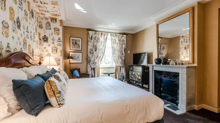 a bedroom with a large bed and a fireplace at Domaine les Crayères in Reims