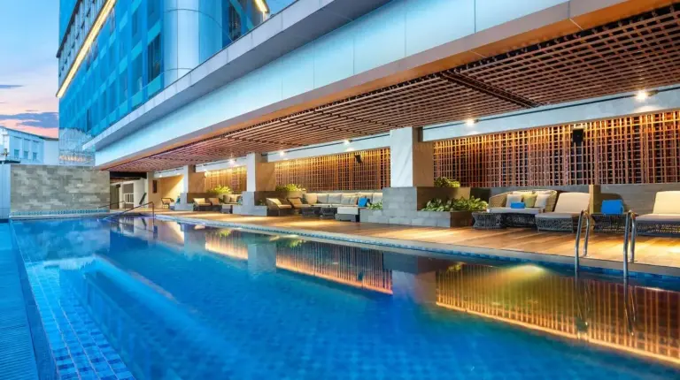 a swimming pool with chairs and a building at DoubleTree by Hilton Surabaya in Surabaya