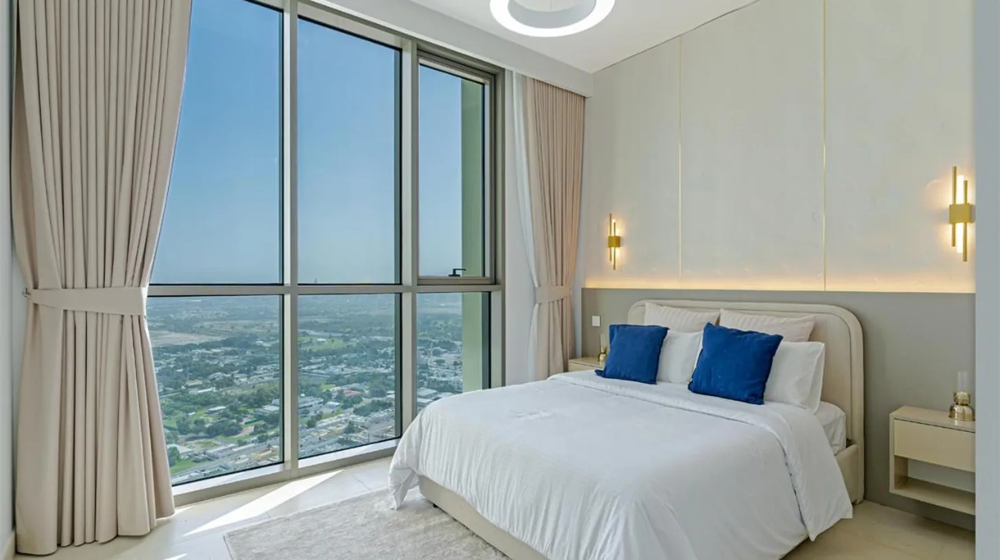 a bedroom with a bed with blue pillows and large windows at Downtown Views 4702 in Dubai