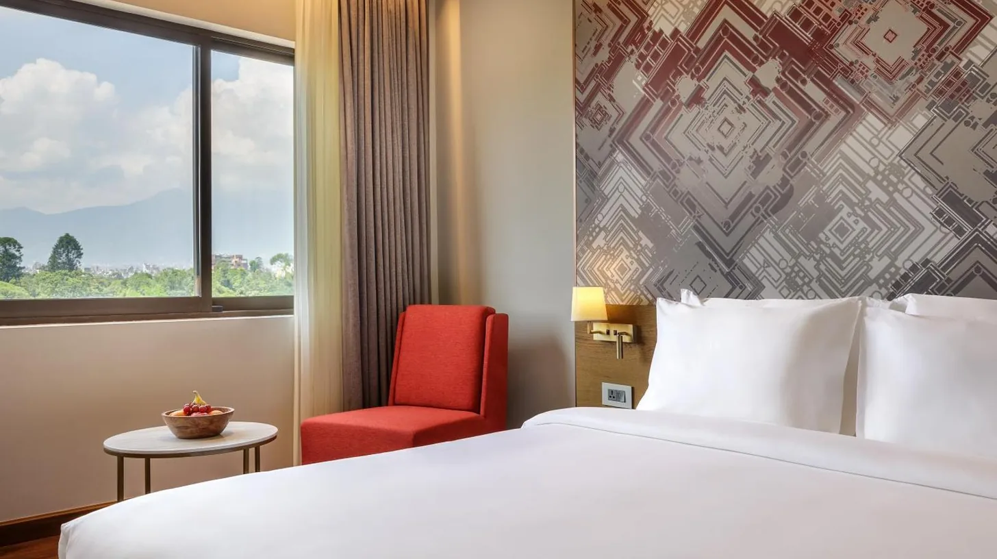 una habitaciÃ³n de hotel con una cama y una silla roja en Dusit Princess Kathmandu en KatmandÃº