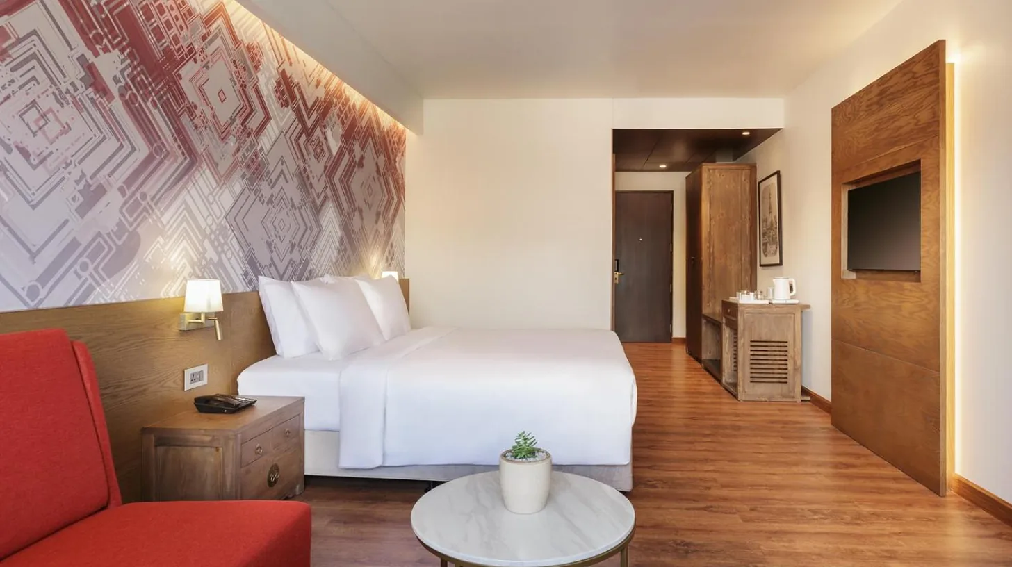 una habitaciÃ³n de hotel con una cama blanca y un sofÃ¡ rojo en Dusit Princess Kathmandu en KatmandÃº