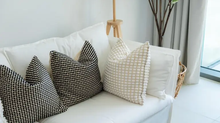 four pillows on a white couch in a living room at Elite Escape Holiday Home - 2 BHK Getaway with Burj Khalifa View and Dubai Mall Access - 1507 in Dubai
