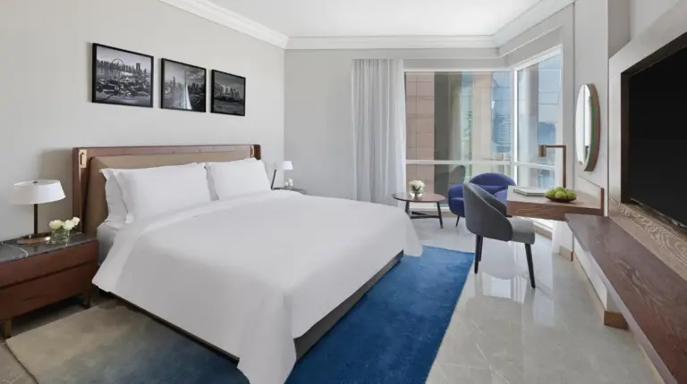 a bedroom with a large bed and a large window at Fairmont Dubai in Dubai