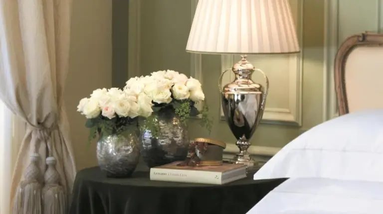 a table with a lamp and flowers and a book at Four Seasons Hotel Firenze in Florence