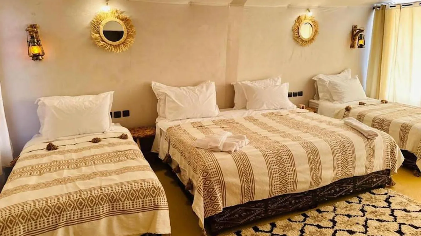 une chambre avec deux lits et un miroir au mur au Golden Dunes Luxury Camp Ã  Merzouga
