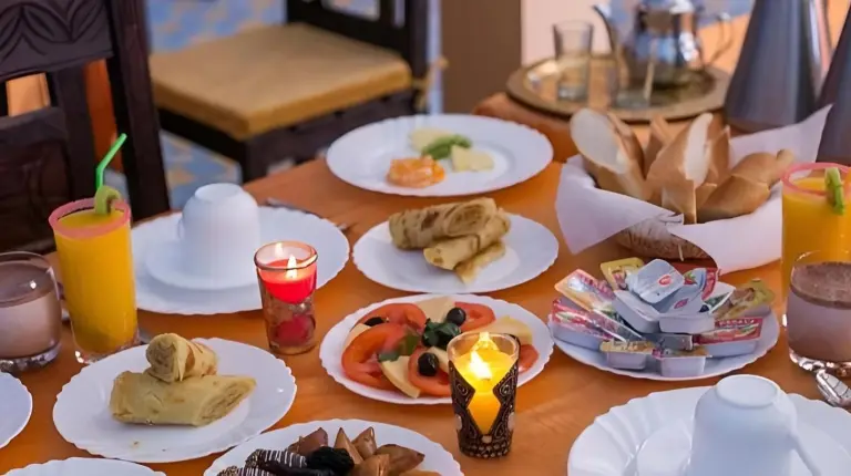 une table en bois avec des assiettes de nourriture dessus au Golden Dunes Luxury Camp Ã  Merzouga