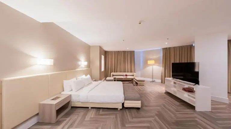 a hotel room with two beds and a couch at Grand Jatra Hotel Balikpapan in Balikpapan