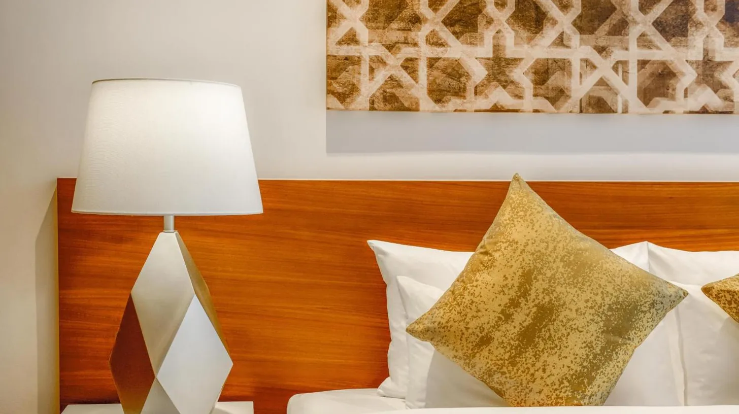 ein Bett mit einer Lampe auf einem Tisch mit Kissen im Grand Mercure Dubai City in Dubai