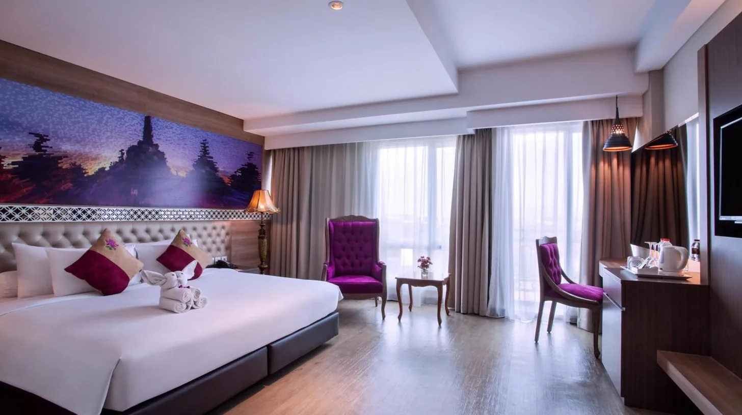 eine Frau, die in einem Hotelzimmer im Grand Mercure Yogyakarta Adi Sucipto in Yogyakarta auf einem rosa Stuhl sitzt