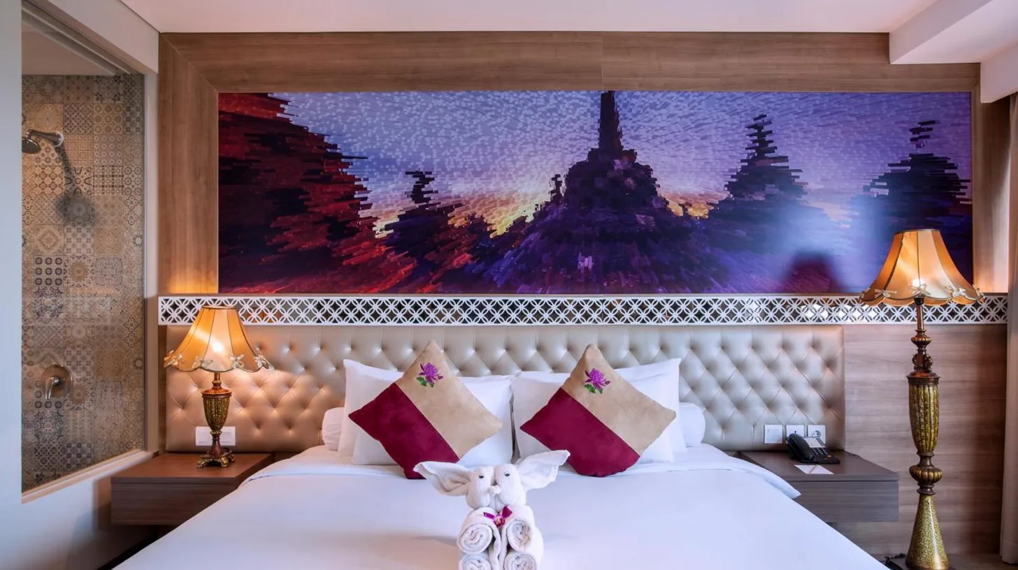 ein Schlafzimmer mit einem großen weißen Bett mit Kissen im Grand Mercure Yogyakarta Adi Sucipto in Yogyakarta