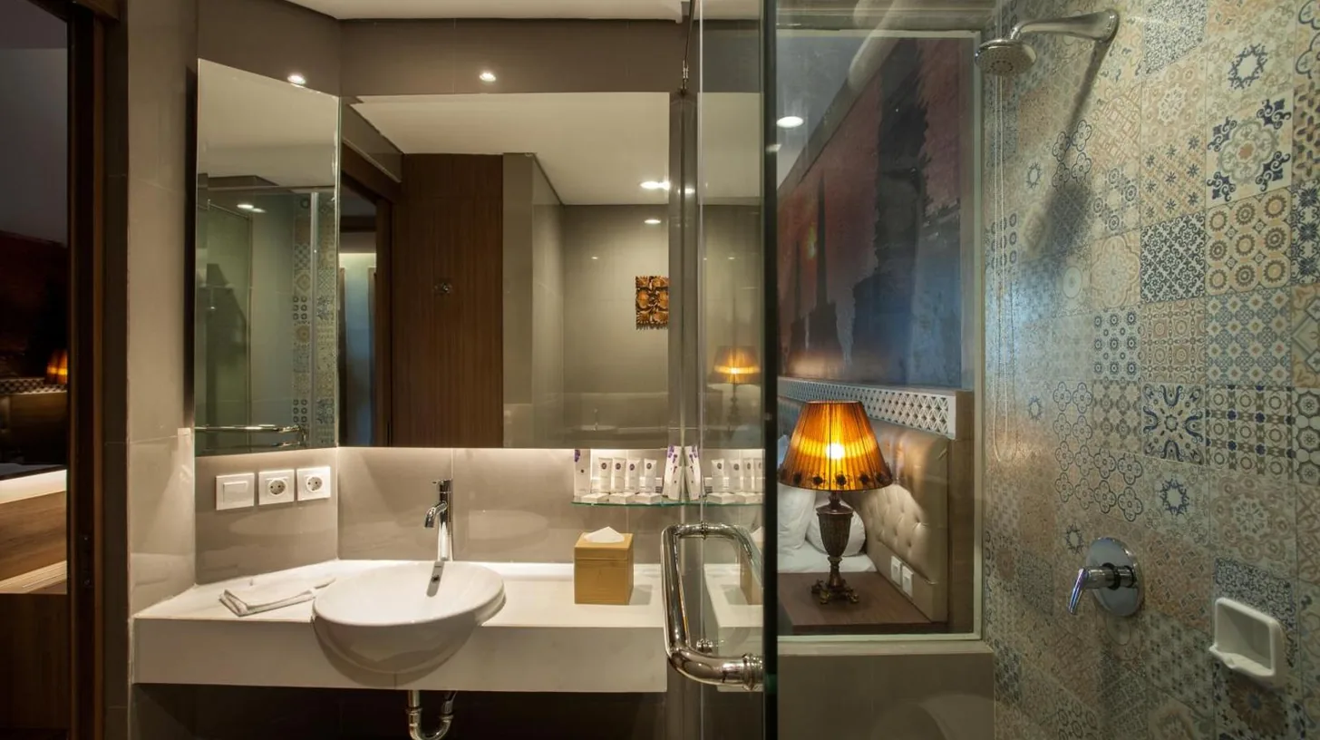 ein Hotelzimmer mit einem großen weißen Bett und einem Schreibtisch im Grand Mercure Yogyakarta Adi Sucipto in Yogyakarta