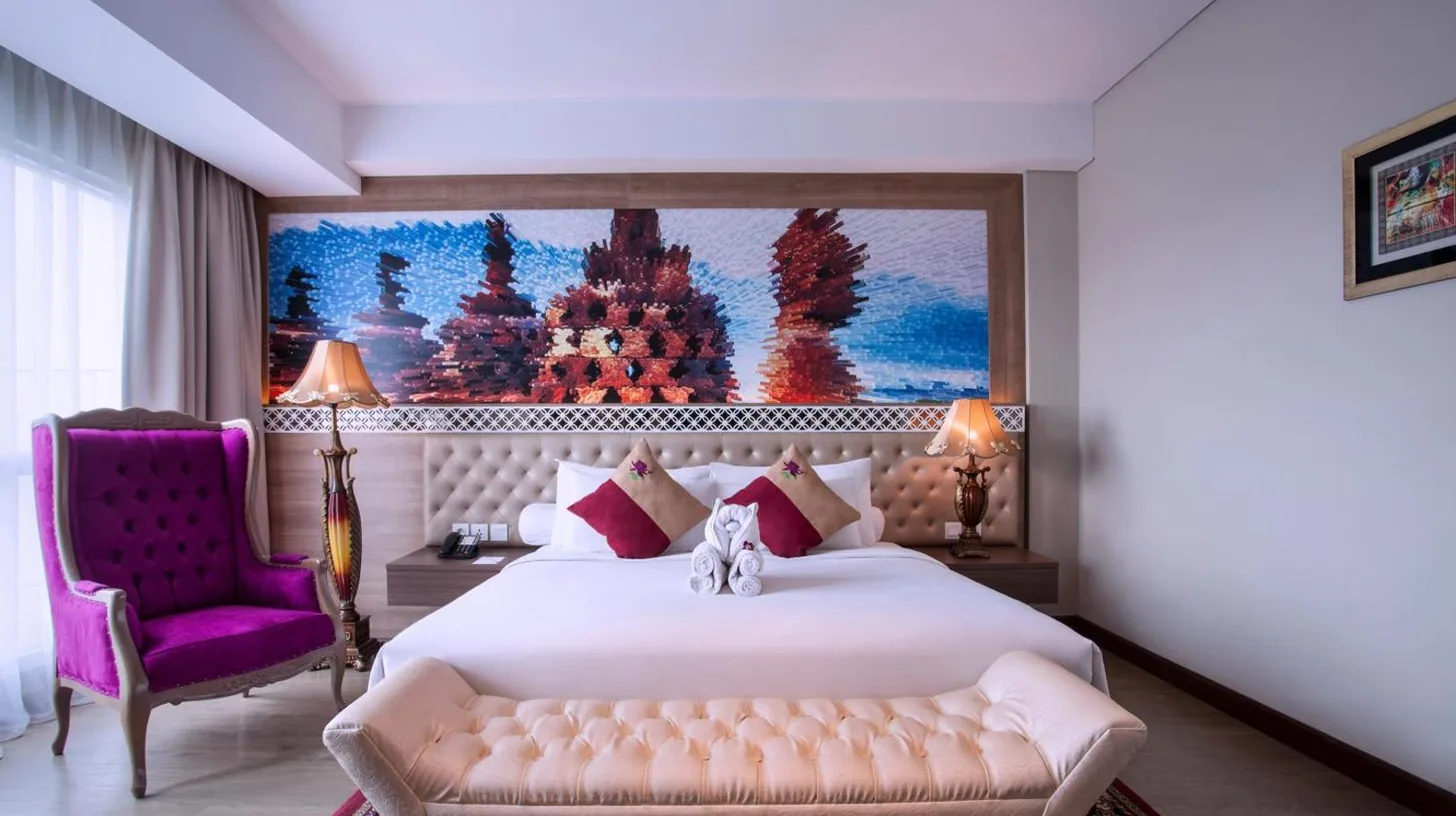 ein Schlafzimmer mit einem großen Bett und einem Fernseher im Grand Mercure Yogyakarta Adi Sucipto in Yogyakarta