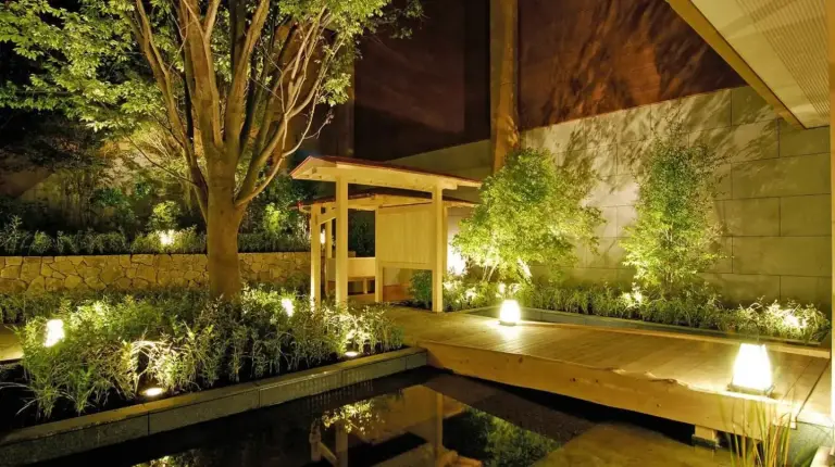 un jardin avec une terrasse en bois et un étang avec des lumières au Hakone Tokinoshizuku à Hakone