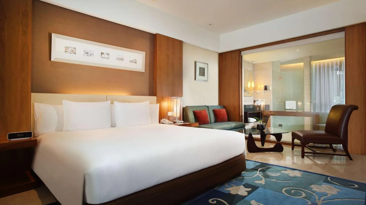 a hotel room with a bed and a large window at Hilton Bandung in Bandung