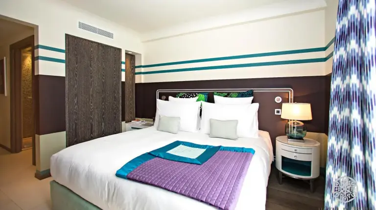 a bedroom with a large bed with a purple blanket on it at Hôtel de Paris Saint-Tropez in Saint-Tropez