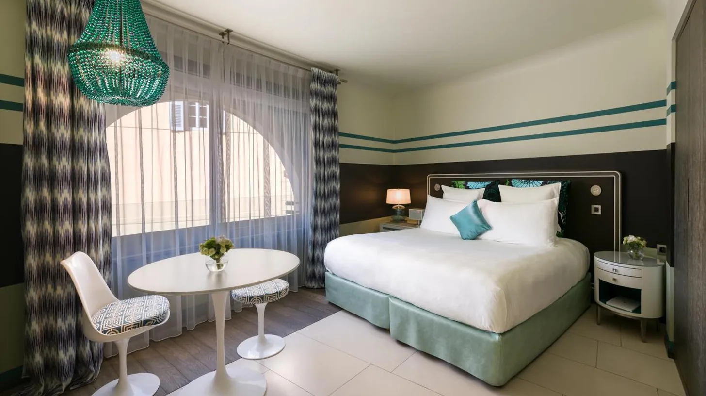 a hotel room with a bed and a table at Hôtel de Paris Saint-Tropez in Saint-Tropez