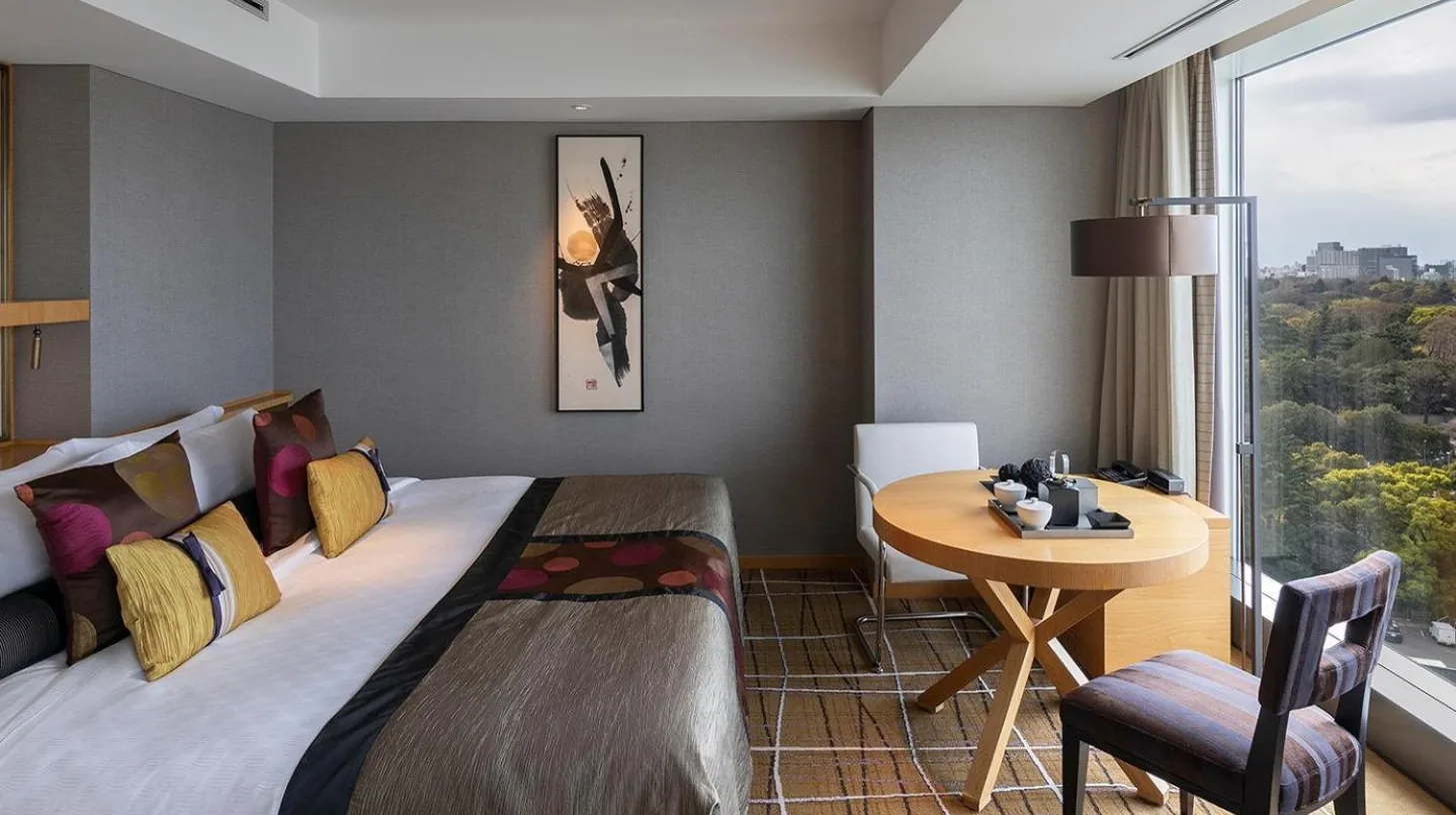 a bedroom with a bed and a table and a window at Hotel New Otani Tokyo EXECUTIVE HOUSE ZEN in Tokyo