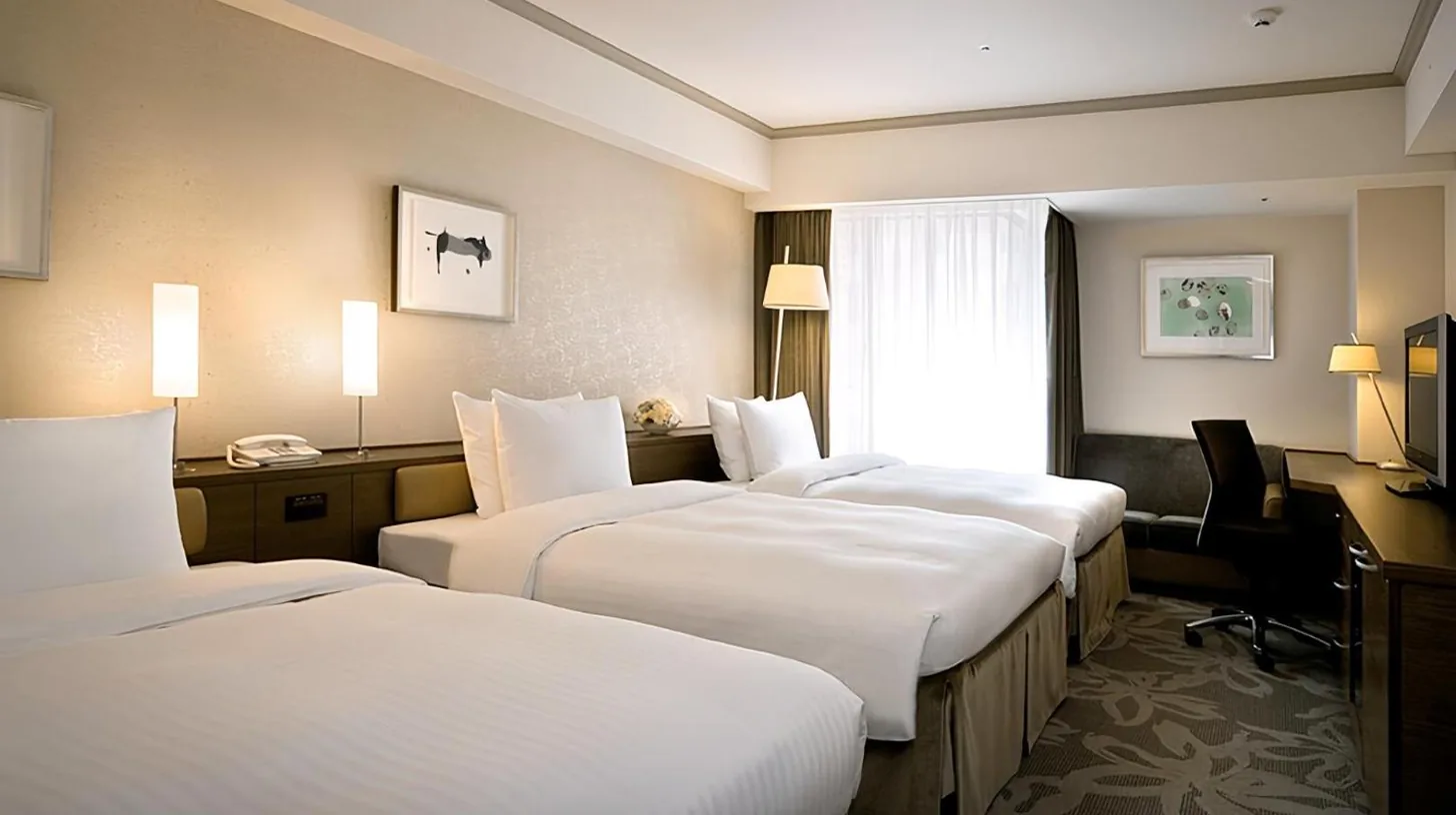 ein Hotelzimmer mit drei Betten und einem Schreibtisch im Hotel Nikko Fukuoka in Fukuoka