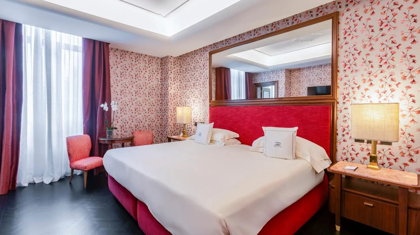 ein Schlafzimmer mit einem groÃen Bett und einem Spiegel im Hotel Regency - Small Luxury Hotels of the World in Florenz