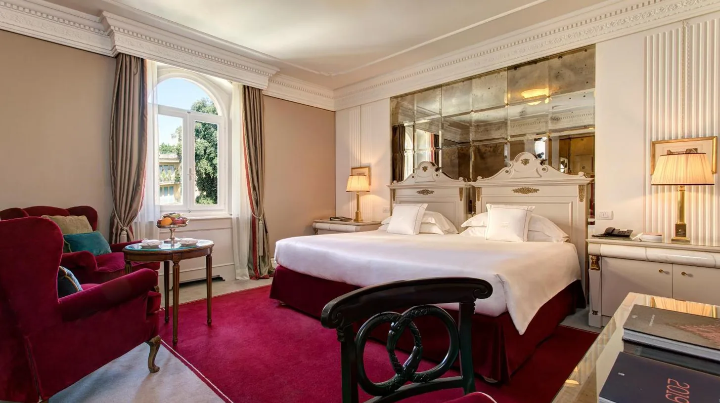 ein Schlafzimmer mit einem groÃen Bett und einem Wohnzimmer im Hotel Regency - Small Luxury Hotels of the World in Florenz