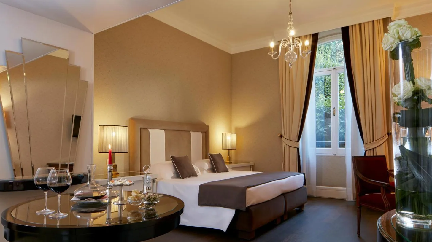 ein Schlafzimmer mit einem Bett und einem Tisch mit WeinglÃ¤sern im Hotel Regency - Small Luxury Hotels of the World in Florenz