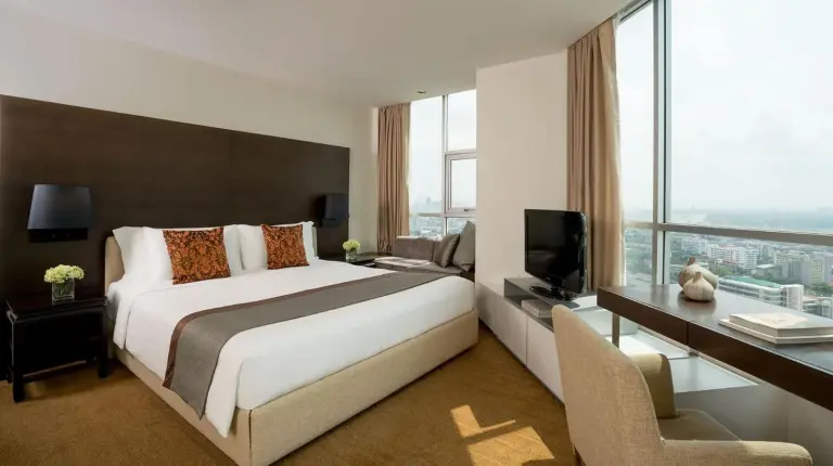 ein Hotelzimmer mit einem groÃen Bett und einem Fernseher im JC Kevin Sathorn Bangkok Hotel in Bangkok