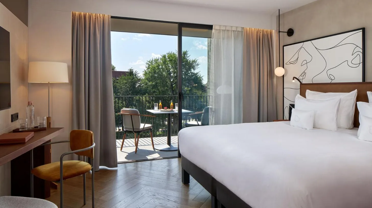 a hotel room with a large bed and a balcony at L'Esquisse Hotel & Spa Colmar - MGallery Collection in Colmar