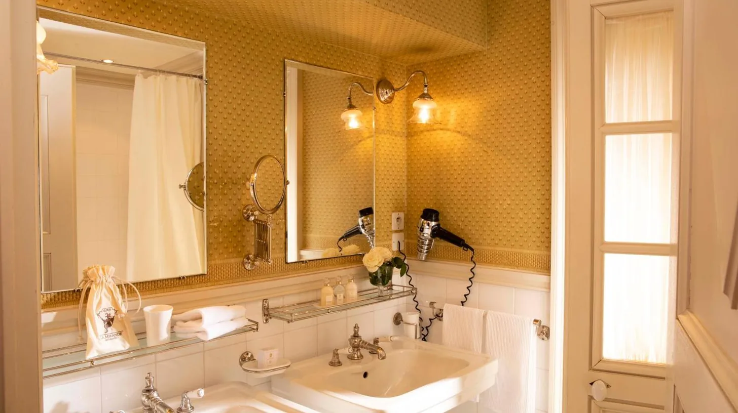 a bathroom with two sinks and a mirror at La Mirande in Avignon