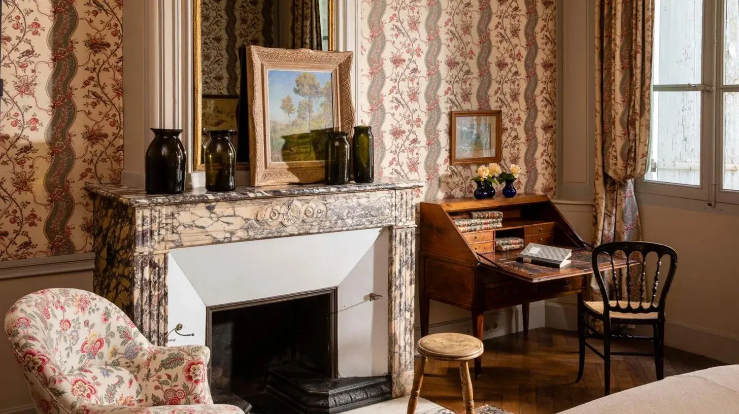 a living room with a fireplace and a chair and a table at La Mirande in Avignon
