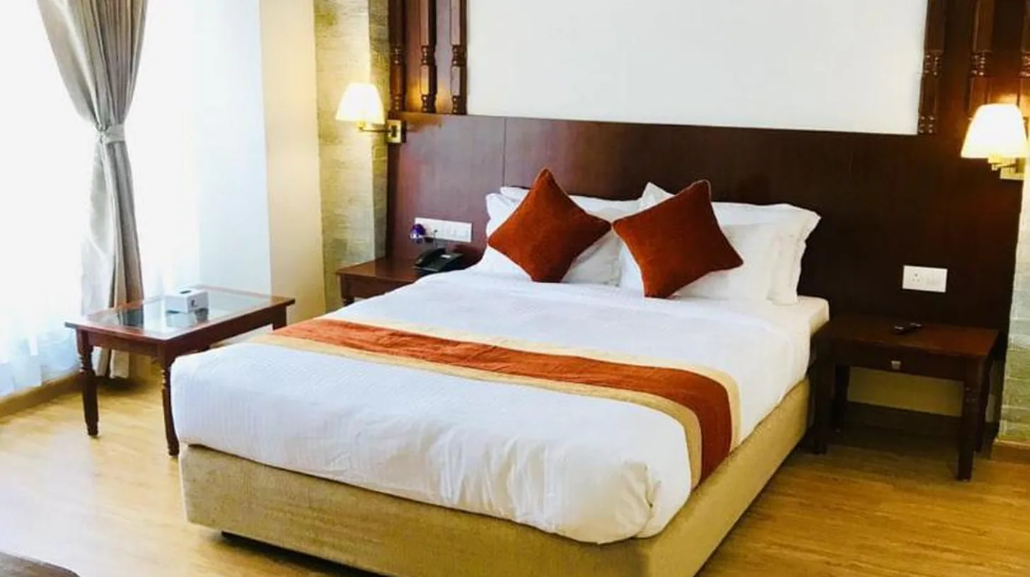 a bedroom with a large bed and a wooden floor at Landmark Pokhara in Pokhara