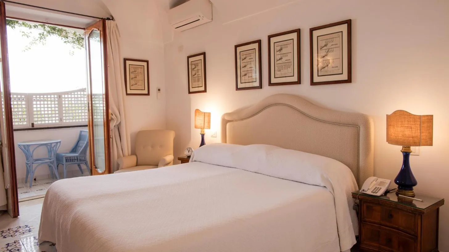 a bedroom with a white bed and a phone at Le Sirenuse in Positano